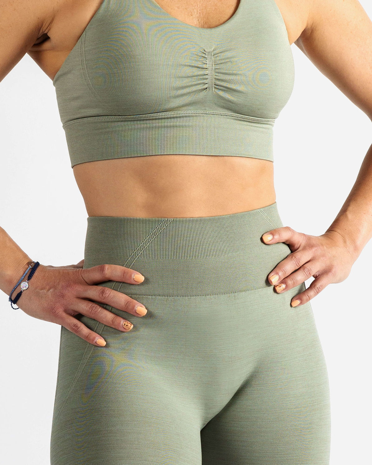 Close-up of sage green High Support Sports Bra showing the front scrunch detail, ribbed texture, and premium 55% nylon, 37% polyester, 8% spandex fabric blend.